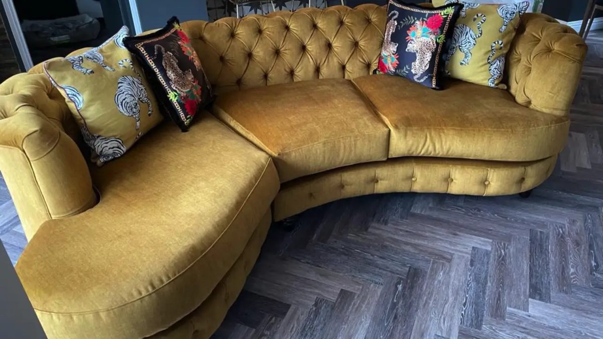 Curved sofa reupholstered in mustard velvet with patterned cushions
