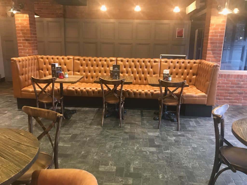 Deep-buttoned tan leather banquette seating in a bar