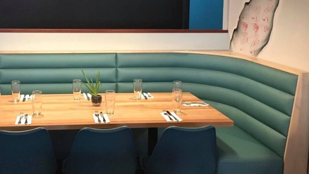 Teal banquette seating with oak tables in a restaurant